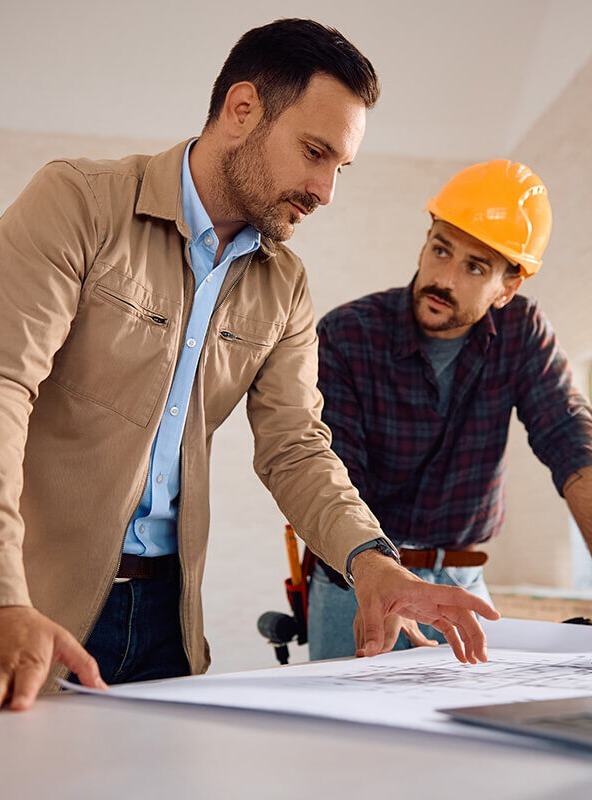 deux-hommes-ordinateur-plan-travaux-logement-casque-professionnel-1